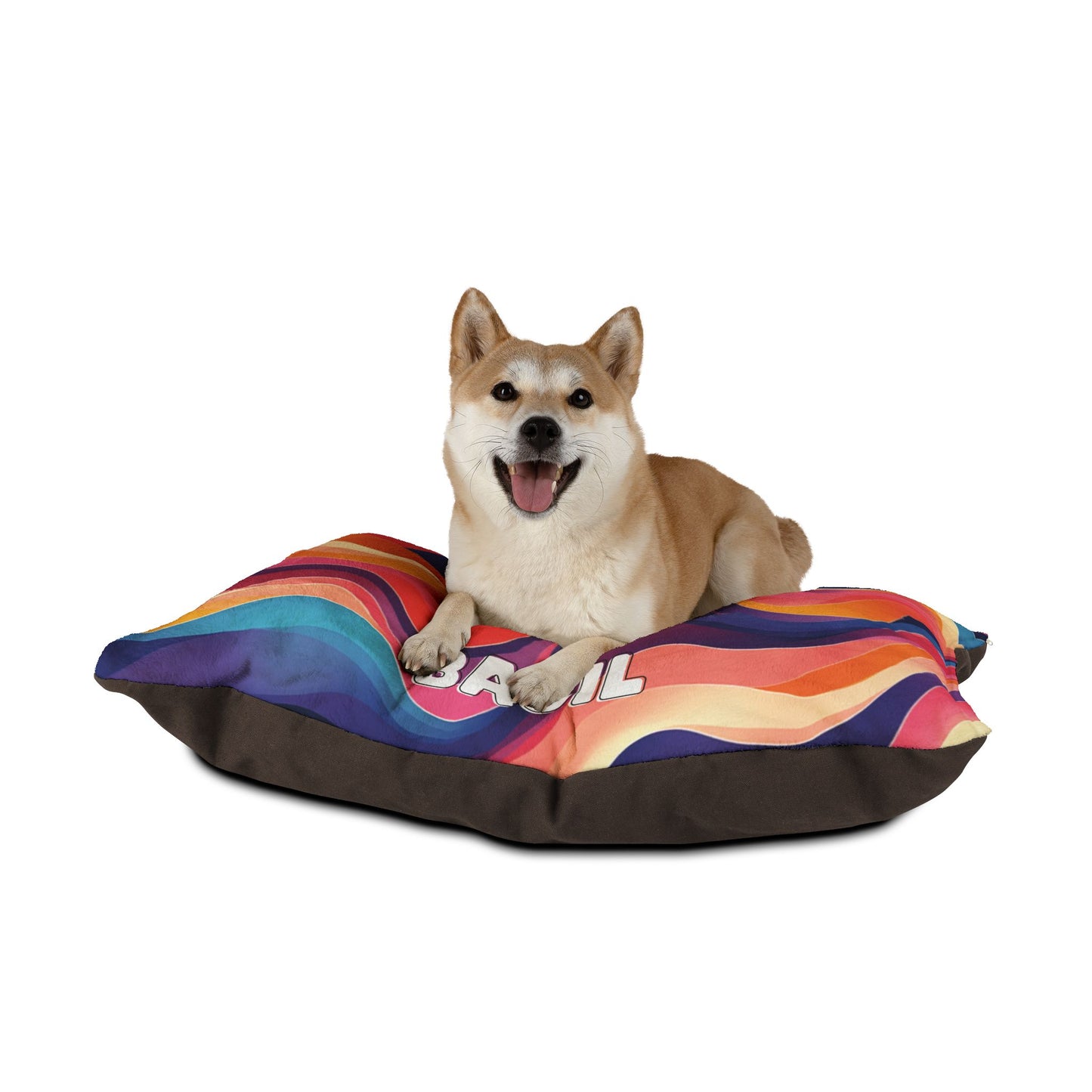 A happy Shiba Inu dog lies on a colorful, African-inspired wavy-patterned pillow with the word CHILL partially visible. The dog faces forward with its mouth open and tongue out, appearing cheerful against a plain white background.