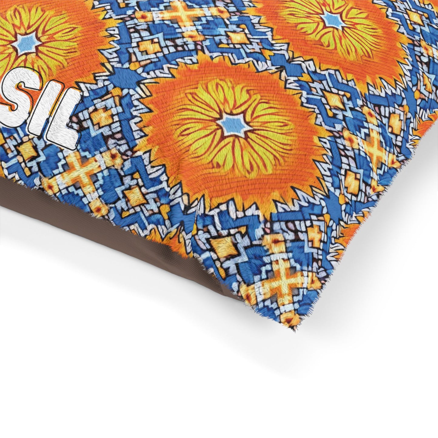 A close-up of a stylish pet bed cushion featuring a bold geometric pattern with large orange and yellow sunburst shapes, blue and white diamond designs, and a partial white text reading SIL on the left side. The background below is plain white.