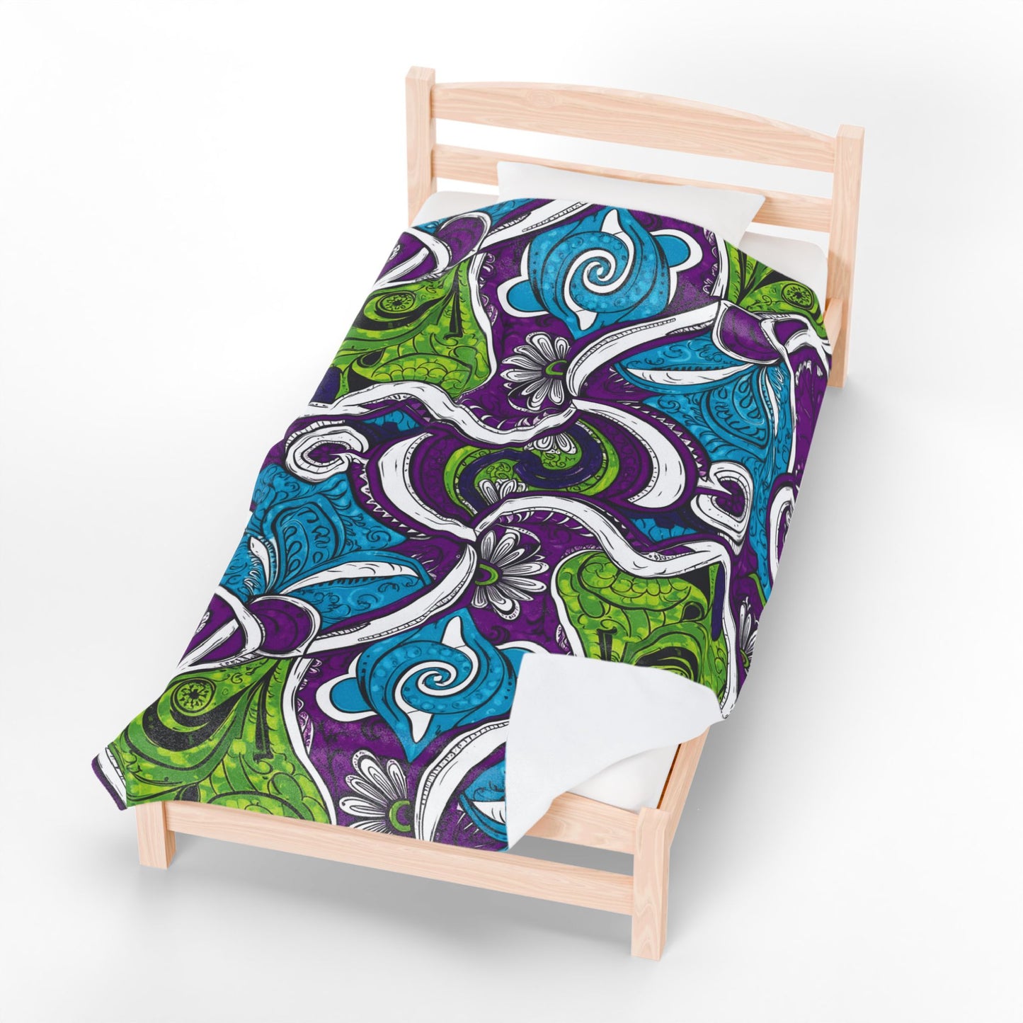 A wooden single bed is topped with a colorful comforter featuring swirling abstract patterns, reminiscent of an African-inspired blanket in green, blue, purple, and white. A white pillow rests at the head of this bold, artistic bedding.