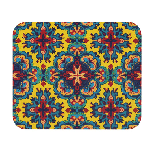 A rectangular mat with rounded corners featuring a vibrant, symmetrical pattern. This African-inspired mouse pad displays blue, red, and orange ornate shapes on bright yellow, with a non-slip rubber base for a stylish and creative desk accessory.