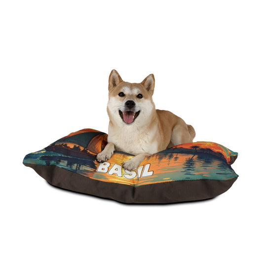 A happy Shiba Inu with upright ears and an open mouth lies on a colorful personalized pet bed featuring a lakeside sunset scene and the name “BASIL.” The white background highlights the dog, luxurious comfort, and unique bed design.