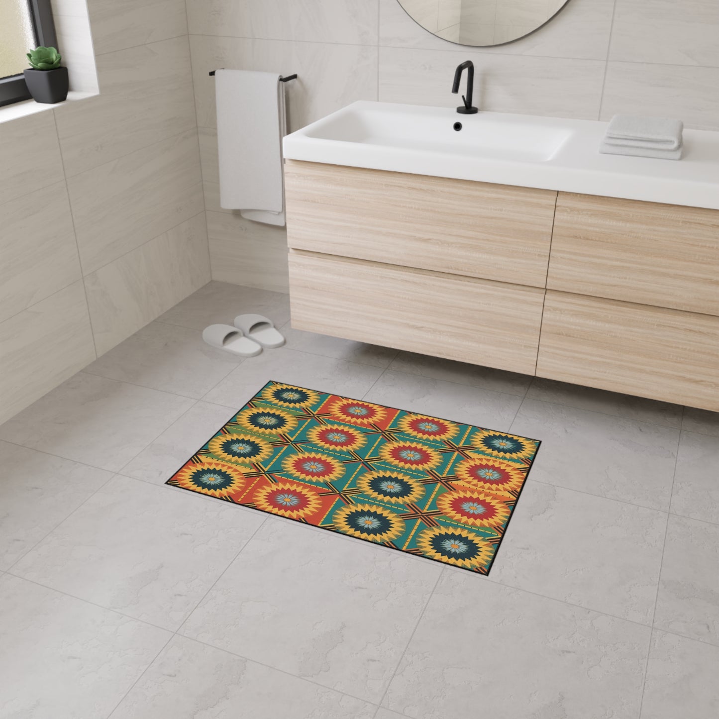 A modern bathroom with light beige tiles, a wooden vanity with a white sink, a round mirror, and white towels. An African-inspired floor mat with a geometric sunburst pattern and non-slip rubber backing adds color to the floor.