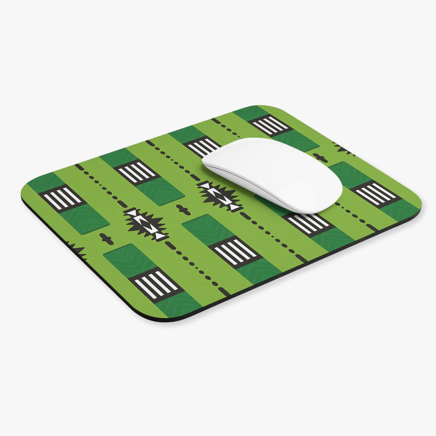 A green rectangular African-inspired mouse pad with a non-slip rubber base features a creative geometric pattern of black, white, and dark green shapes. A white wireless mouse rests on top, making this a stylish and creative desk accessory.