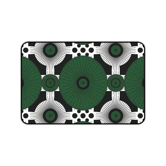Rectangular neoprene desk mat with a bold geometric pattern: large green circles radiate in a grid, surrounded by smaller black and white circles, sunburst shapes, and black dots on black. A clean, modern colorful workspace accessory with symmetrical design.