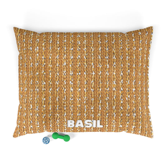 A stylish dog bed in textured brown, personalized with “BASIL” in bold white letters. Next to this personalized pet bed are two toys—a green bone-shaped chew and a blue ball with white holes—seen from above.