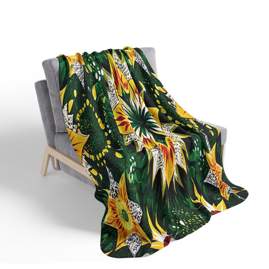 A gray chair draped with an African-inspired fleece blanket featuring bold yellow, orange, and white star-shaped flowers with green leaves and abstract accents. The sherpa fleece cascades onto the floor, adding unique flair to your home decor.