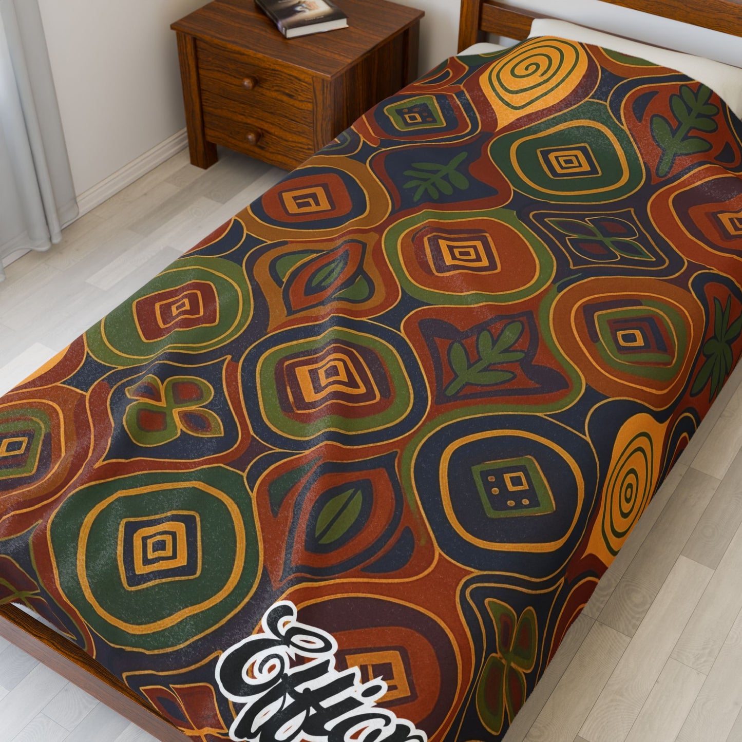 A twin bed features an African-inspired blanket with a colorful geometric abstract pattern in red, green, yellow, brown, and blue. The word Elfin is written in white script at the corner—perfect as a unique custom gift.