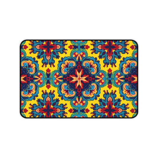 A rectangular Neoprene desk mat with an intricate, symmetrical floral pattern in red, blue, teal, and orange on a bright yellow background. This ergonomic desk mat adds a kaleidoscopic flair as a colorful workspace accessory within a thin black border.