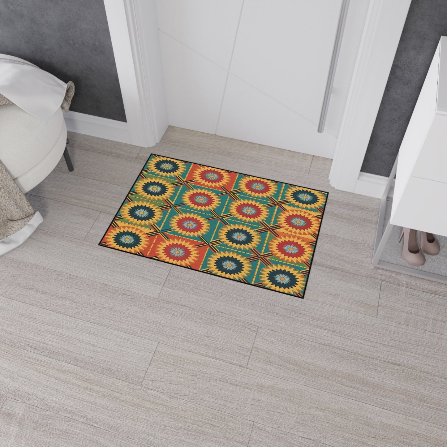 A colorful rectangular rug with a geometric sunburst pattern inspired by African-inspired aesthetics in yellow, red, green, and blue lies on a light wood floor in a modern entryway next to a white cabinet, shoes, and a round upholstered stool.