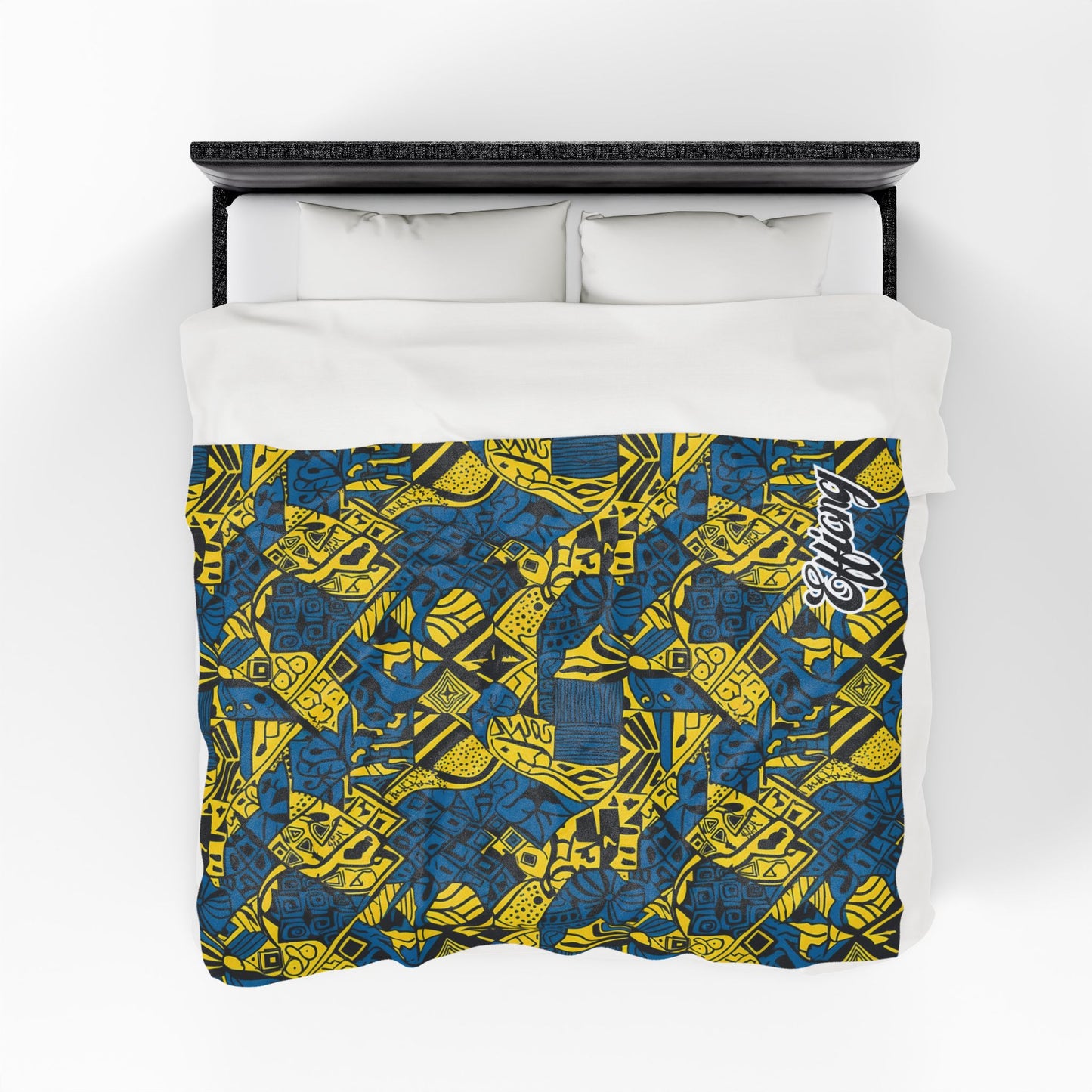 Overhead view of a bed with white pillows and a personalized velveteen blanket featuring a vibrant blue and yellow geometric and abstract pattern. Overlapping shapes, lines, and “Respect” in white script highlight this unique custom gift.