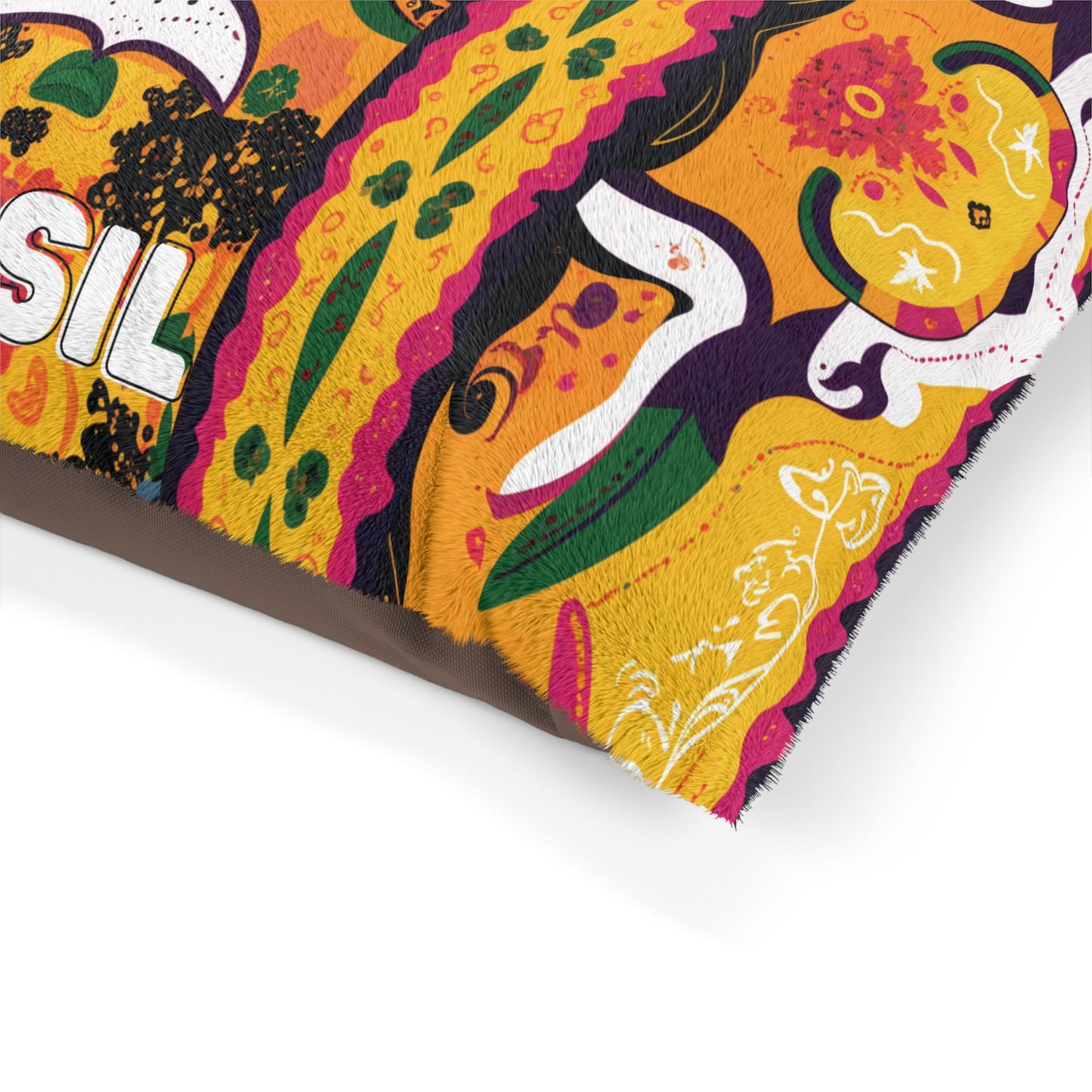 Close-up of a colorful, African-inspired cushion with embroidered patterns in orange, yellow, green, black, white, and pink. The design features flowers, leaves, and abstract shapes on vibrant fabric; the word SIL is partially visible.