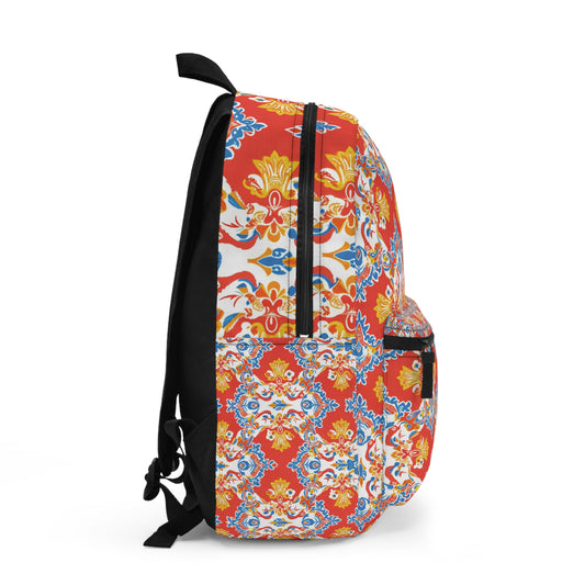 Side view of an African-inspired backpack with a vibrant floral and geometric pattern in red, yellow, blue, and white. It features a black zipper, padded straps, front pocket, and side pocket, set against a plain white background.
