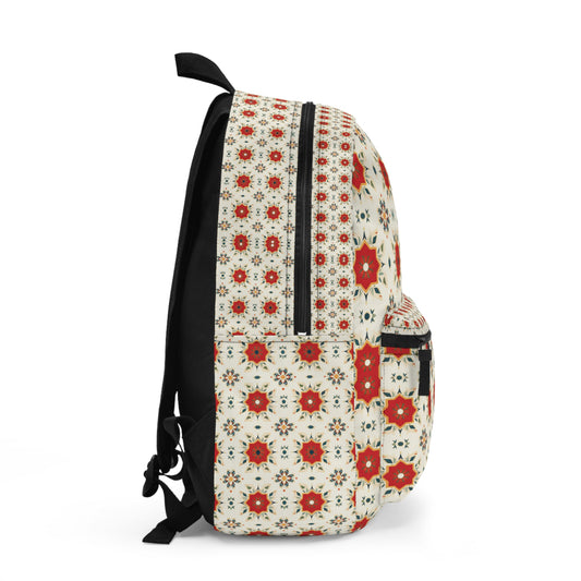 A side view of an African-inspired backpack featuring a repeating geometric floral pattern in red, white, and black on a cream background. The travel backpack has a front pocket, black zipper, shoulder strap, and handle. The pattern covers the entire surface.