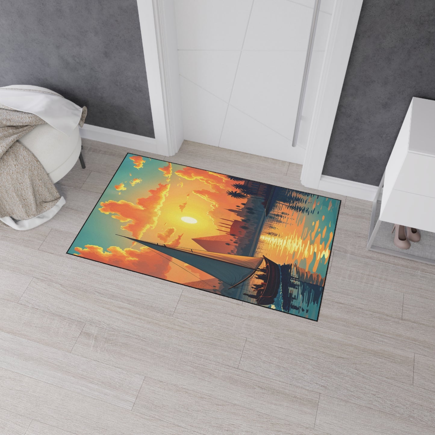 A colorful rectangular custom floor mat with an illustration of a sailboat on water at sunset, glowing clouds, and reflections features non-slip rubber backing. Placed near a white door with a woven blanket and shoes, the setting is bright and modern.
