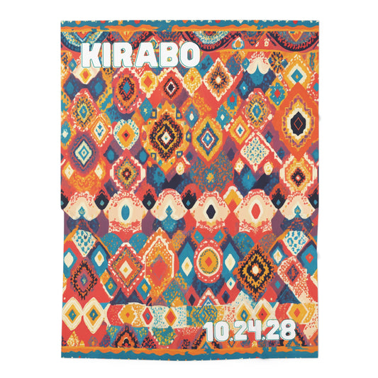 A colorful, geometric patterned textile inspired by African-inspired decor, featuring diamond and oval shapes in red, orange, blue, yellow, and white. The word KIRABO appears in large white letters at the top left, with 10.24.28 at the bottom right.