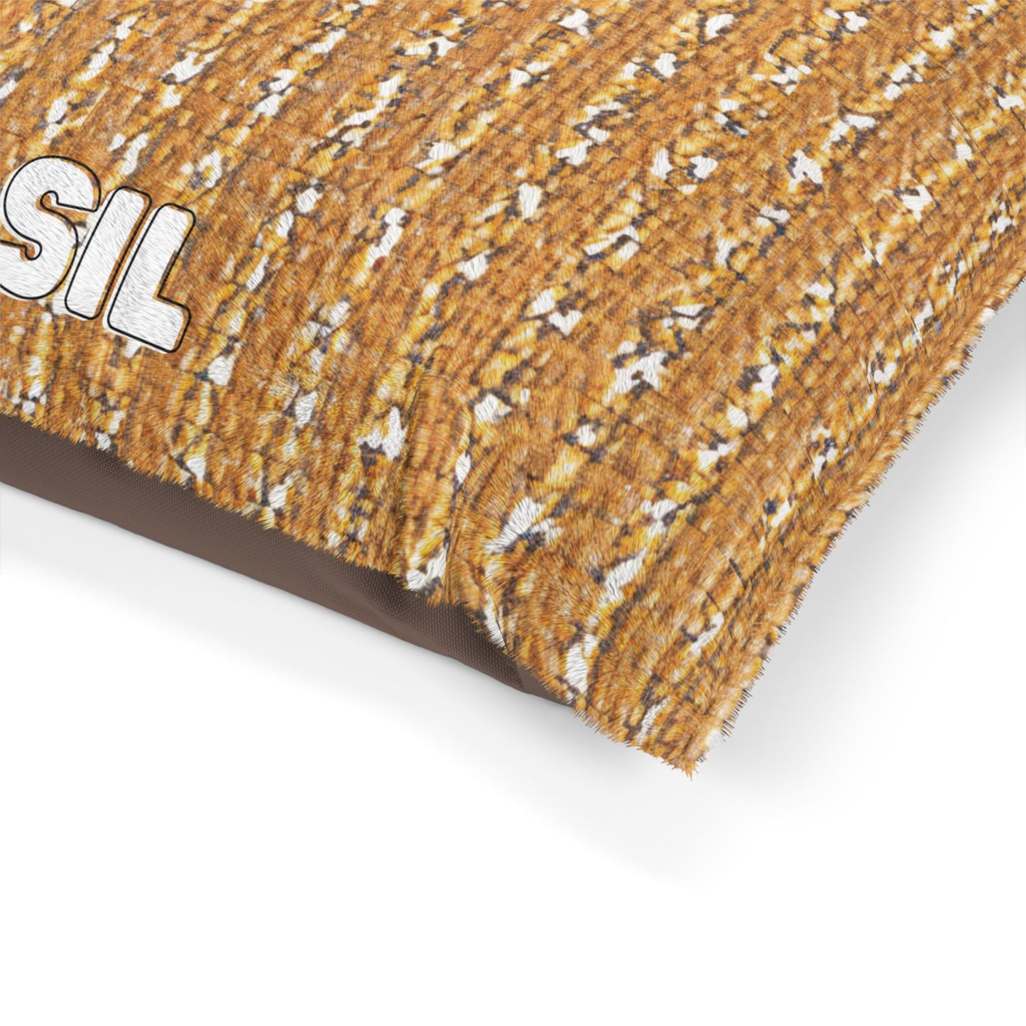 A close-up of a stylish pet bed pillow with a textured design resembling orange and white popcorn kernels. Part of the word “SIL” in bold white letters with a black outline is visible on the upper left side. The lower right edge is slightly folded.