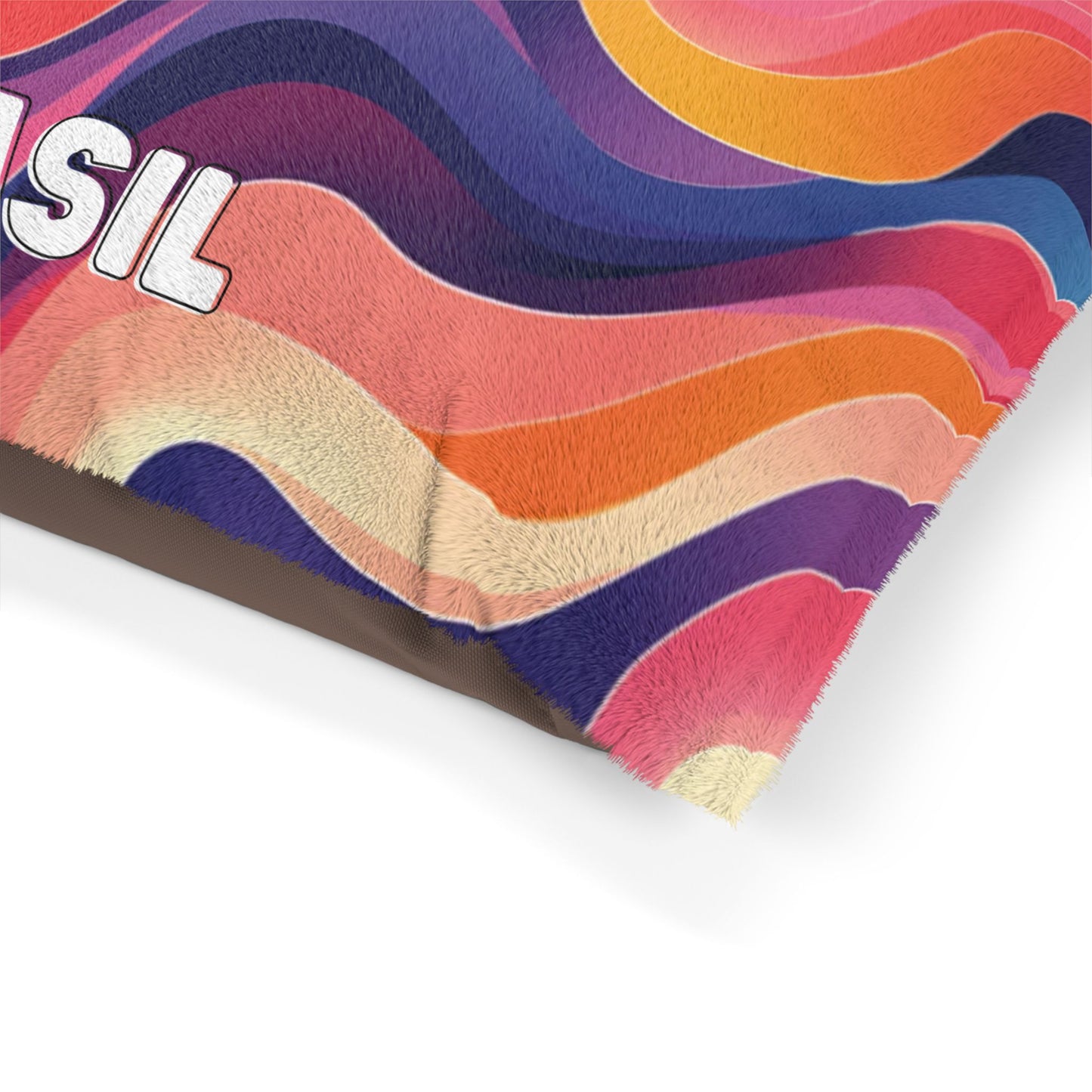 A close-up of a fuzzy blanket corner featuring wavy, African-inspired multicolored stripes in pink, purple, orange, yellow, and blue. The edge shows white plush material, with bold white letters SIL on the upper left. The background is white.