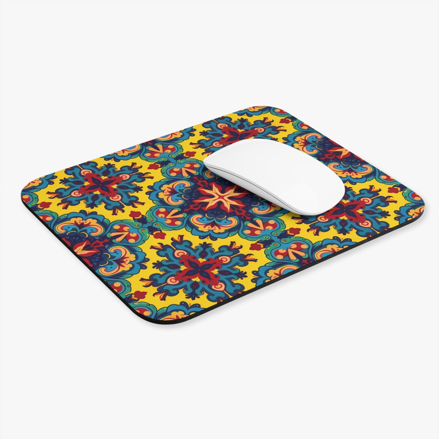 A white computer mouse rests on a rectangular African-inspired mouse pad with a vibrant, multicolored floral and geometric pattern on a bright yellow background. Featuring a non-slip rubber base, this vibrant desk accessory adds flair to any white workspace.