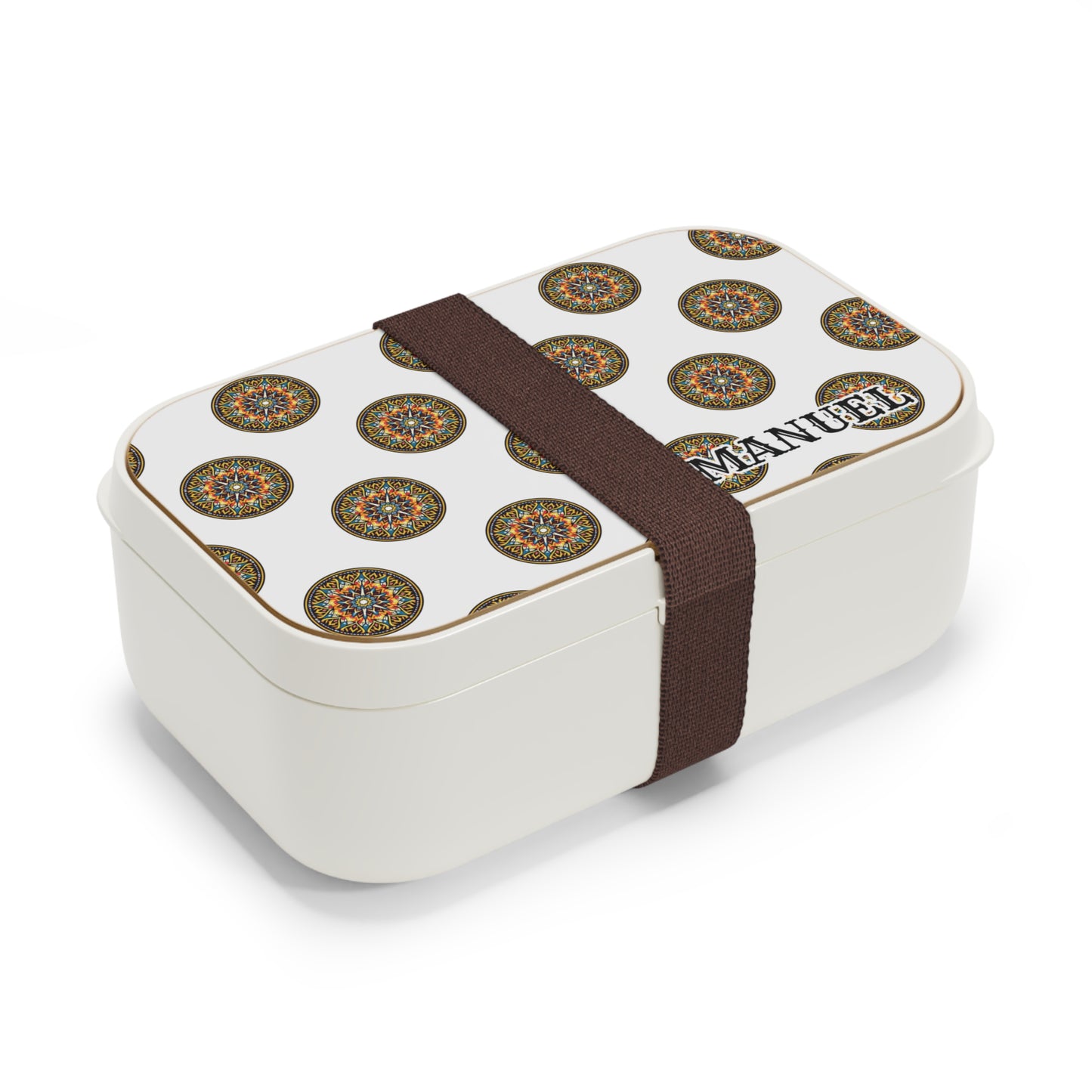 A rectangular BPA-free lunchbox with a decorative lid featuring a repeating circular mandala pattern and the name MANUEL printed in bold letters. A wide brown elastic strap secures this personalized lunch box for daily convenience.