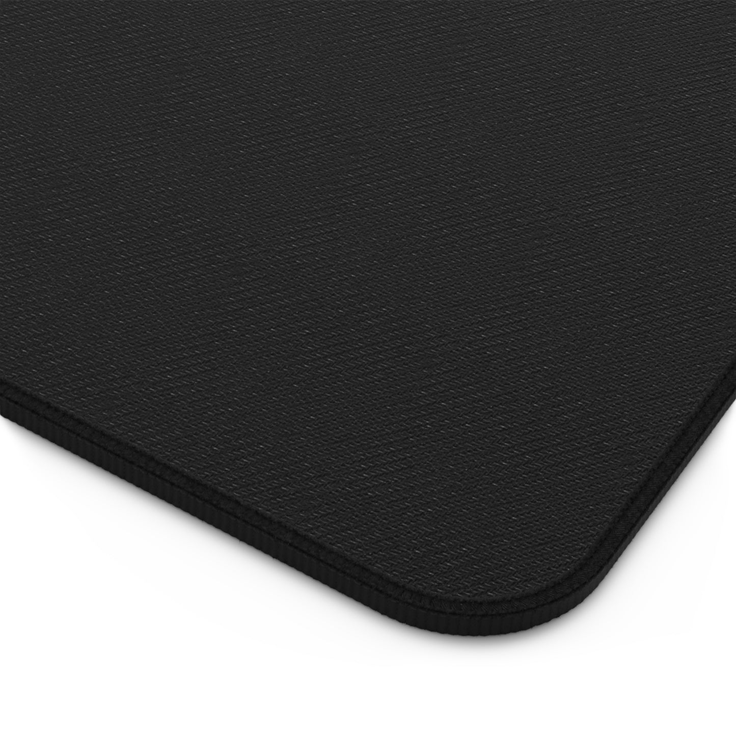 Close-up of the corner of a rectangular black neoprene desk mat with a textured fabric surface and rounded edges. The stitched edge prevents fraying, while the white background highlights this ergonomic desk mat’s sleek design.