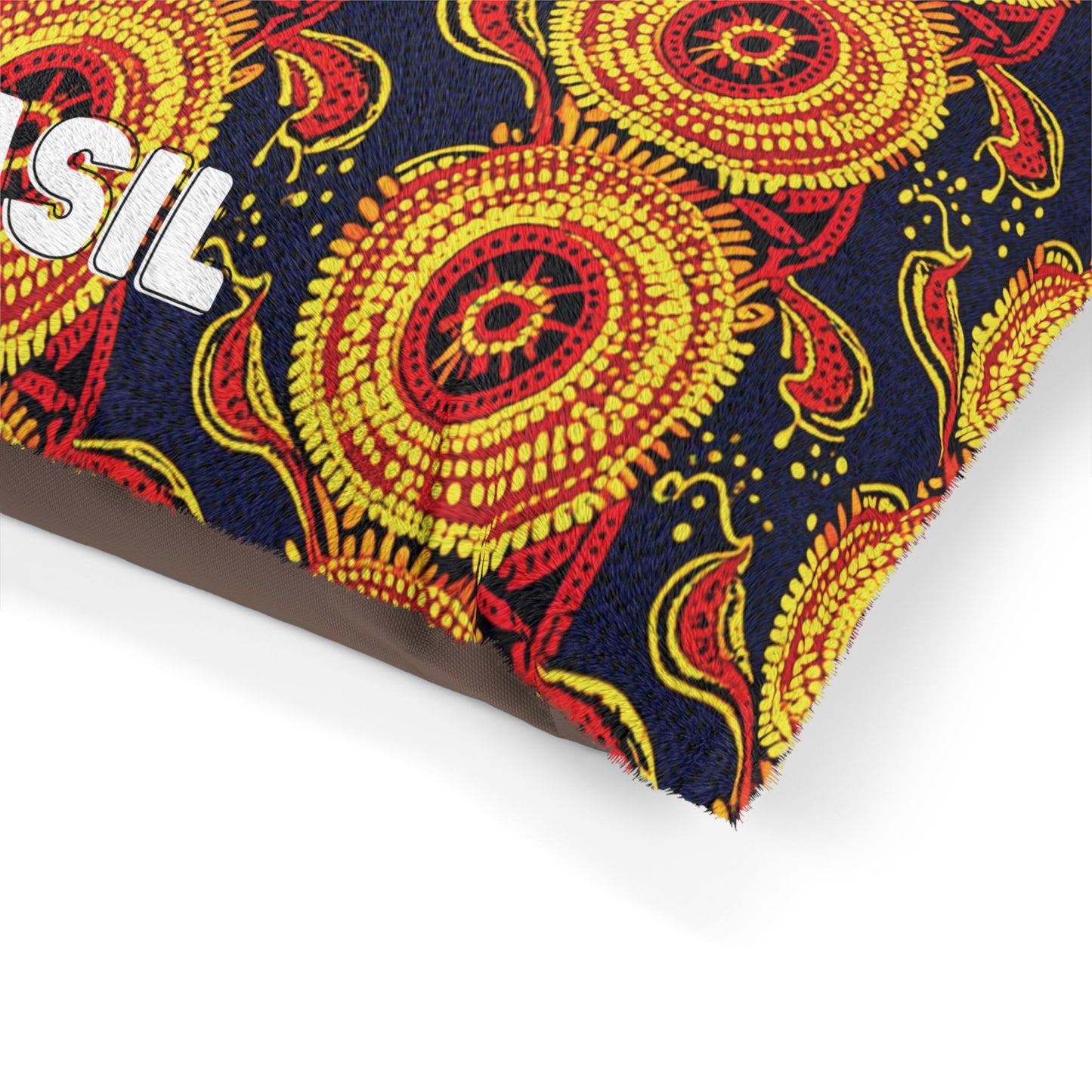 A close-up of a rectangular object wrapped in vibrant African-inspired fabric featuring red, yellow, and orange circular and paisley patterns on a dark blue background. White embroidered letters SIL are partially visible on the fabric’s surface.