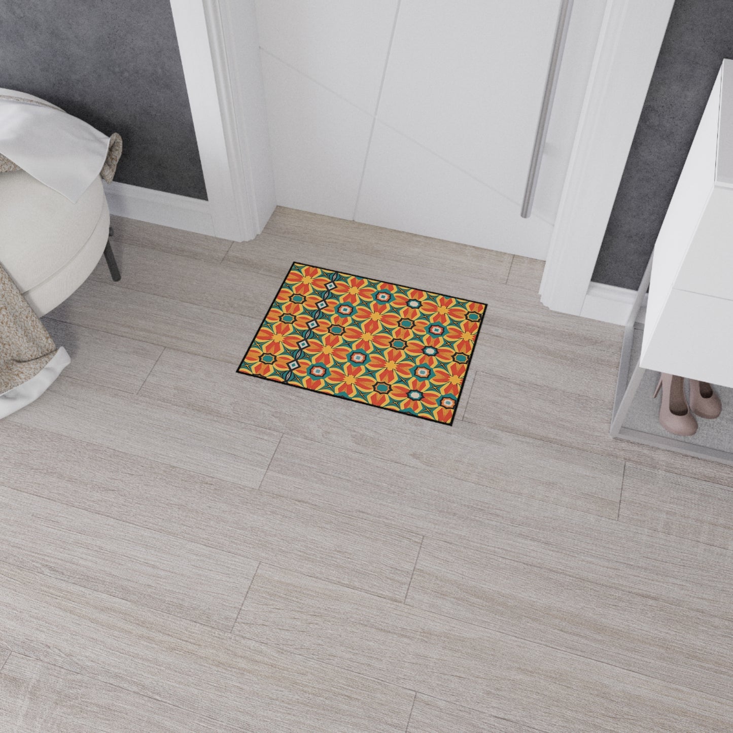 A small doormat with a bright, geometric floral pattern in orange, yellow, and green lies on a light wood floor in front of a white door—an eye-catching piece of African-inspired home decor with non-slip rubber backing for safety.