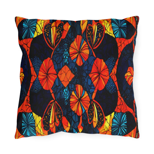 This water-resistant square pillow features a bold, symmetrical pattern with bright orange, red, yellow, and blue floral and leaf shapes on a dark navy background, creating a stained-glass effect with rich colors and intricate black outlines.