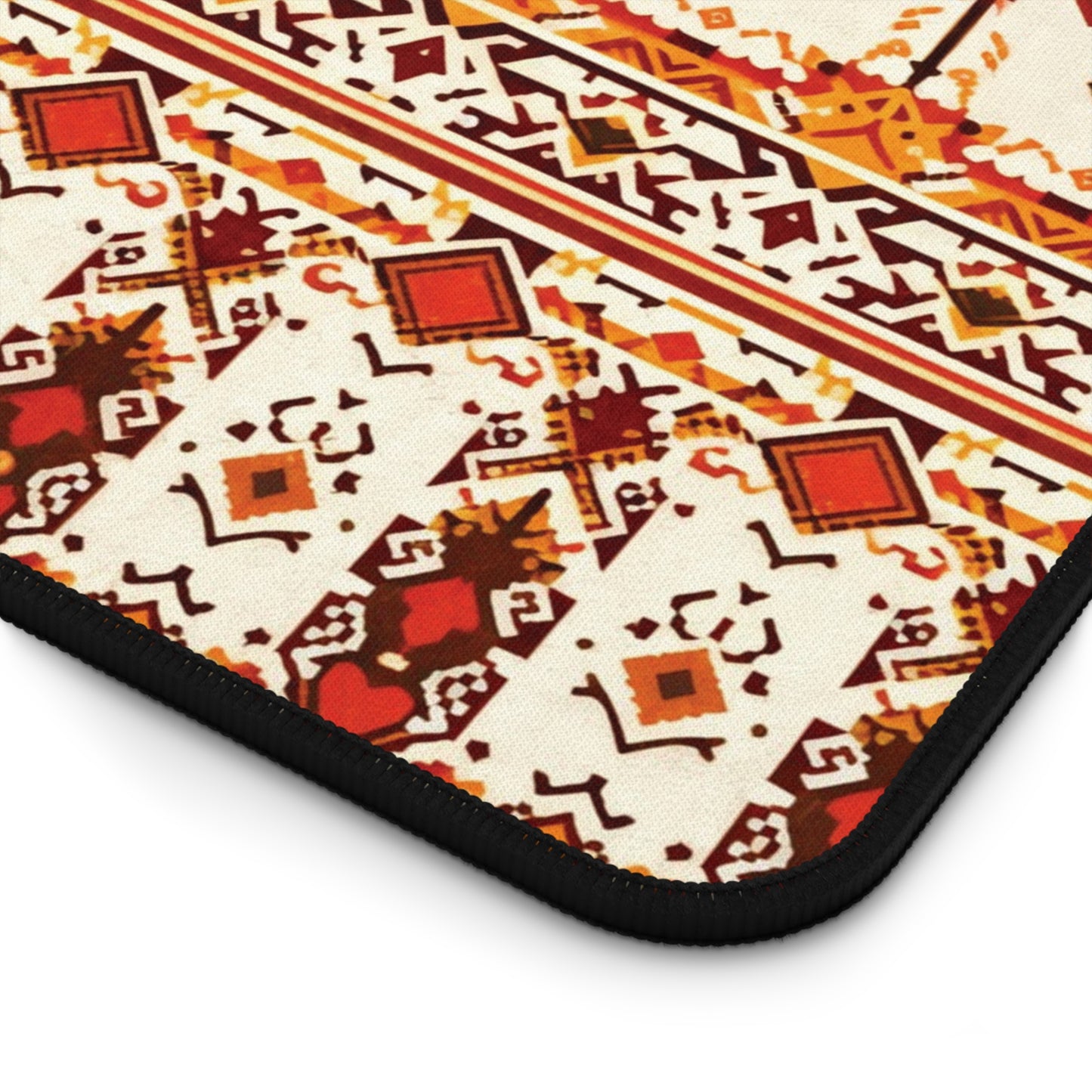 A close-up of a patterned neoprene desk mat with geometric shapes in red, yellow, brown, and orange on a cream background. Diamonds, zigzags, and intricate motifs stand out, bordered by black stitching—perfect as a colorful workspace accessory.