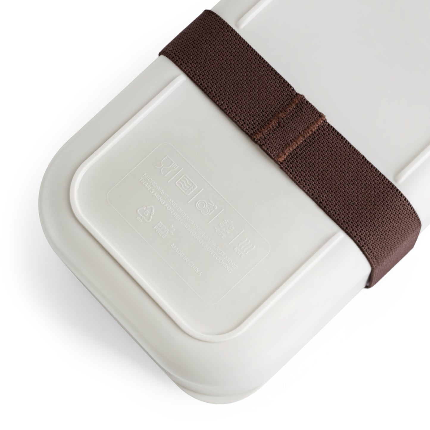 A close-up of a beige personalized bento box with embossed Korean writing, recycling symbols, and “Made in Korea.” A wide brown elastic strap secures the lid. The background is white and minimalistic.