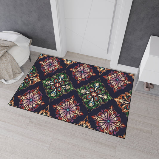 A rectangular rug with colorful, ornate, symmetrical floral patterns inspired by African-inspired aesthetics sits on light wood flooring near a white door. The rug’s non-slip rubber backing keeps it secure beside a cozy chair and white cabinet displaying beige heels.