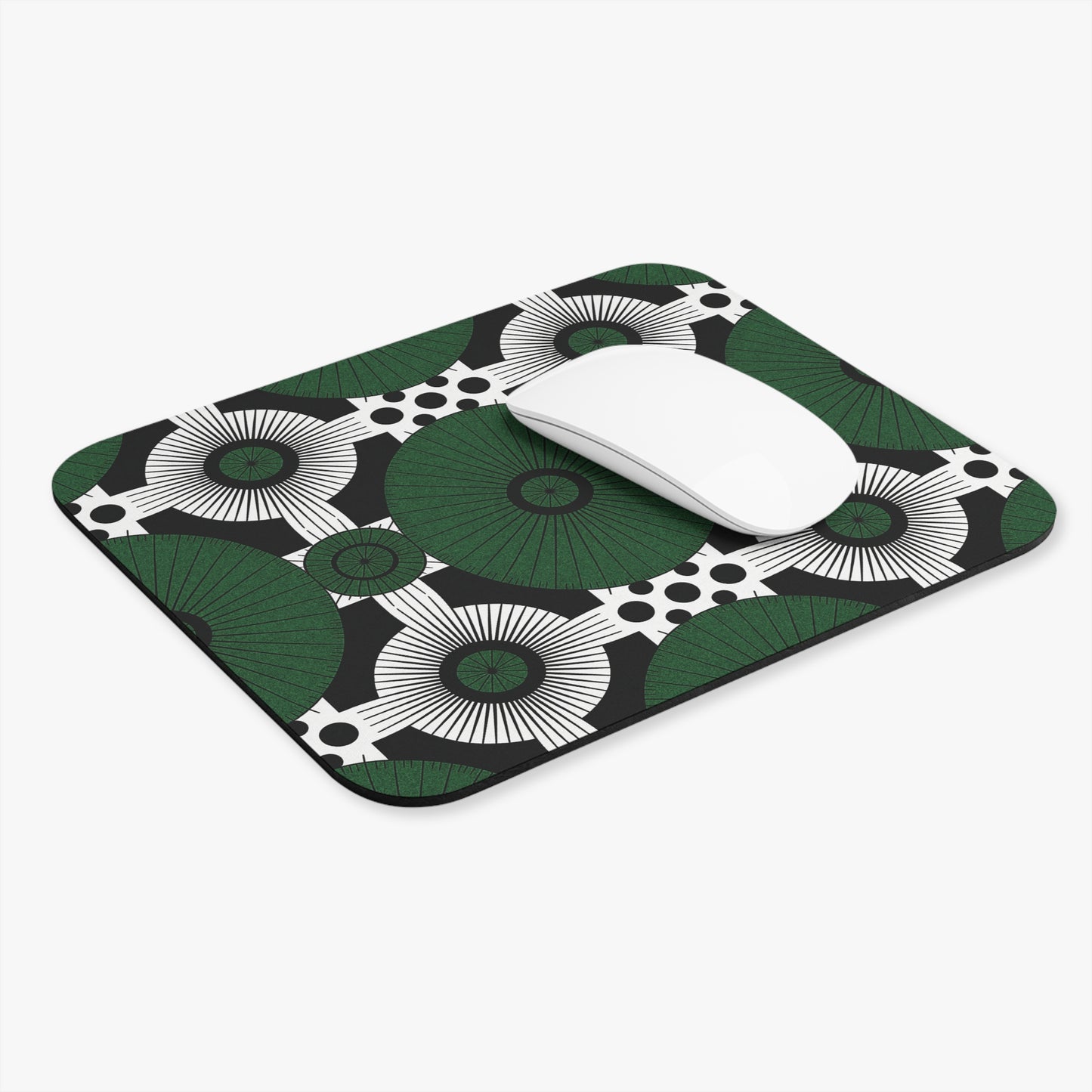 A white wireless mouse sits on a rectangular African-inspired mouse pad, a vibrant desk accessory featuring overlapping green and white fan shapes with radiating black lines, set against a non-slip rubber base and a black background scattered with white dots.