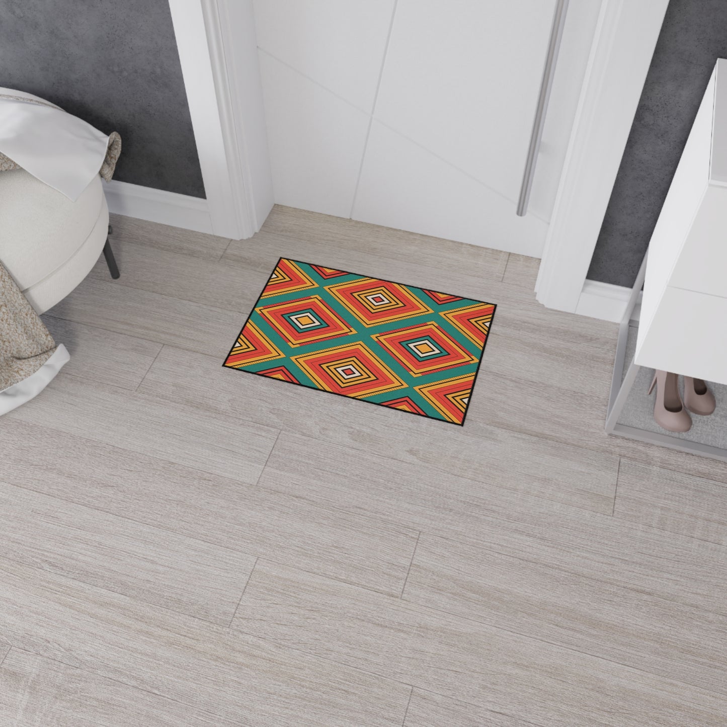 Colorful, non-slip doormat with a geometric diamond pattern in red, orange, blue, green, and yellow adds an African-inspired touch to a modern entryway with light wood flooring, white cabinetry with shoes beneath, and gray accent walls.