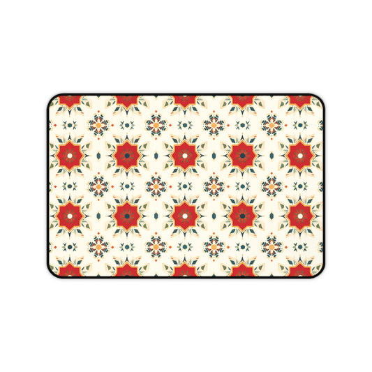 A rectangular Neoprene desk mat with a repeating geometric pattern features red eight-pointed stars with green and orange accents, surrounded by smaller floral and diamond shapes on a cream-colored background, all outlined in black—a colorful workspace accessory.