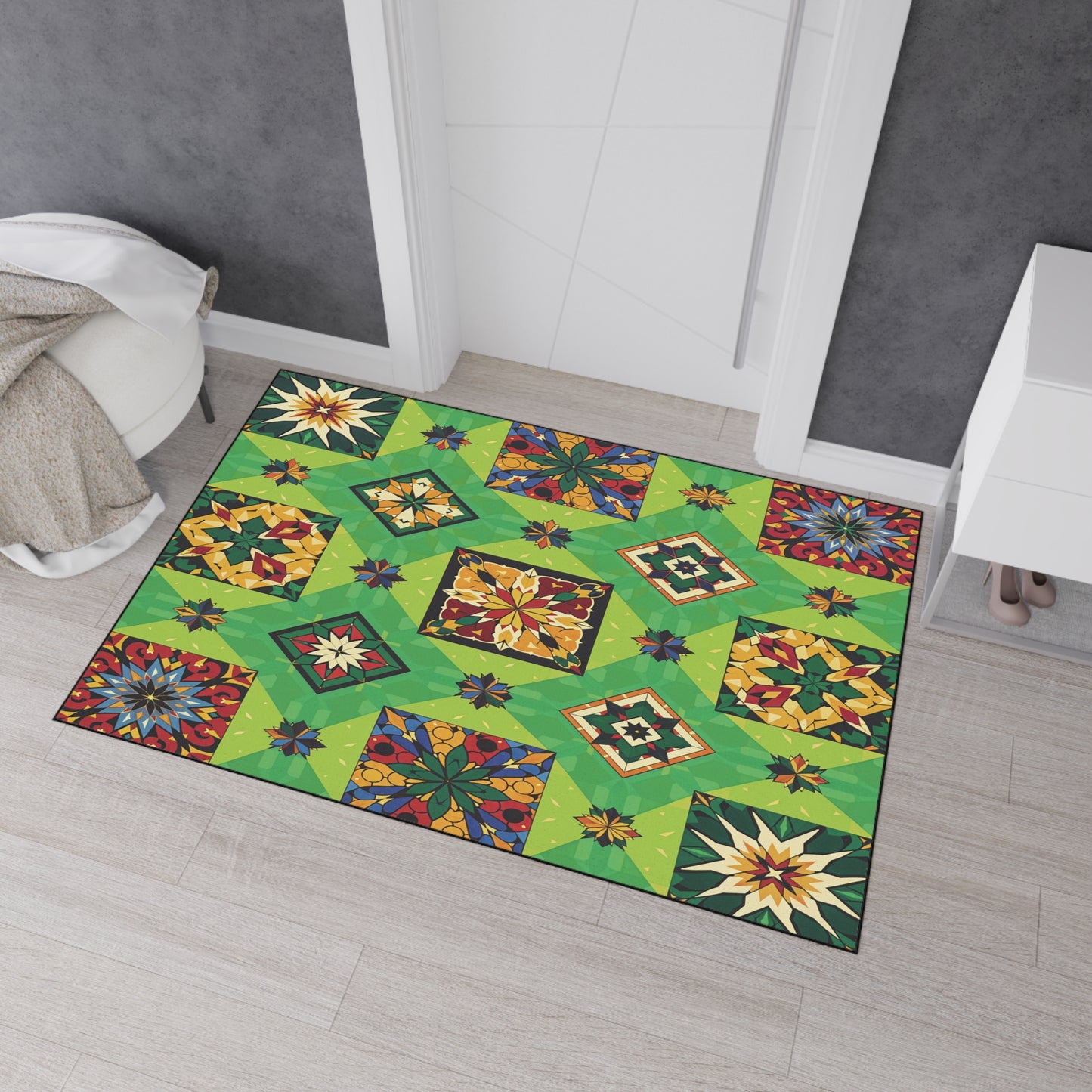 A colorful, non-slip rug with a patchwork of geometric and floral patterns in green, yellow, blue, red, and orange lies on a light wood floor near a white dresser, gray wall, and draped chair in this modern room.