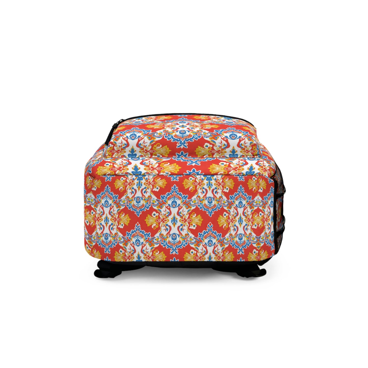 A square, cushioned ottoman with black legs is shown, featuring a vibrant red, yellow, and blue floral and geometric pattern inspired by African-inspired backpack designs. A zippered side pocket is visible on the right. The ottoman is centered on a white background.