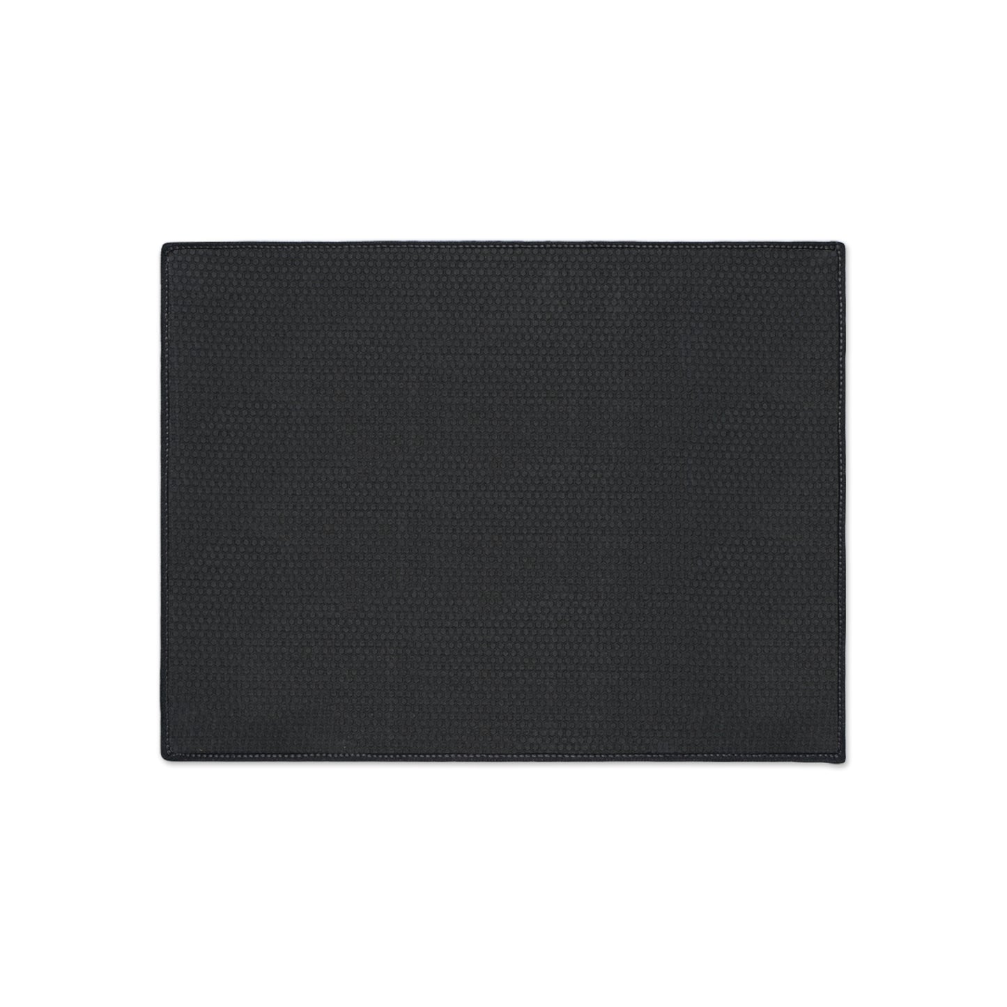 A rectangular, flat, black textured mat with stitched edges is centered on a white background. Featuring a non-slip rubber backing, the mat boasts a fine, uniform pattern and showcases its simple and minimalist design from above.