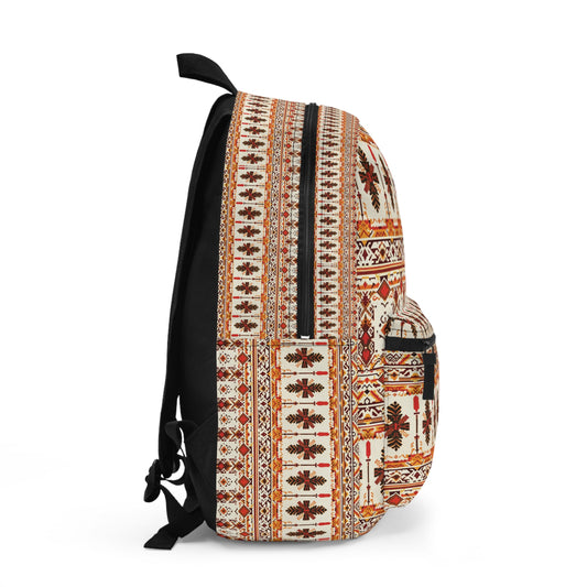A side view of a vibrant backpack featuring a traditional, multicolored geometric and floral pattern in shades of red, orange, and black on a cream background. This boho chic rucksack has a zippered main compartment, front pocket, and solid black straps.