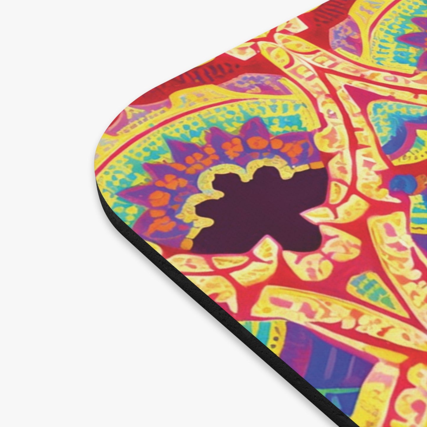 Close-up of a colorful, African-inspired mouse pad with a non-slip rubber base. The pattern features vibrant reds, yellows, blues, and purples in bold, curving lines and flower-like shapes on a smooth, flat surface with black edges—a perfect desk accessory.