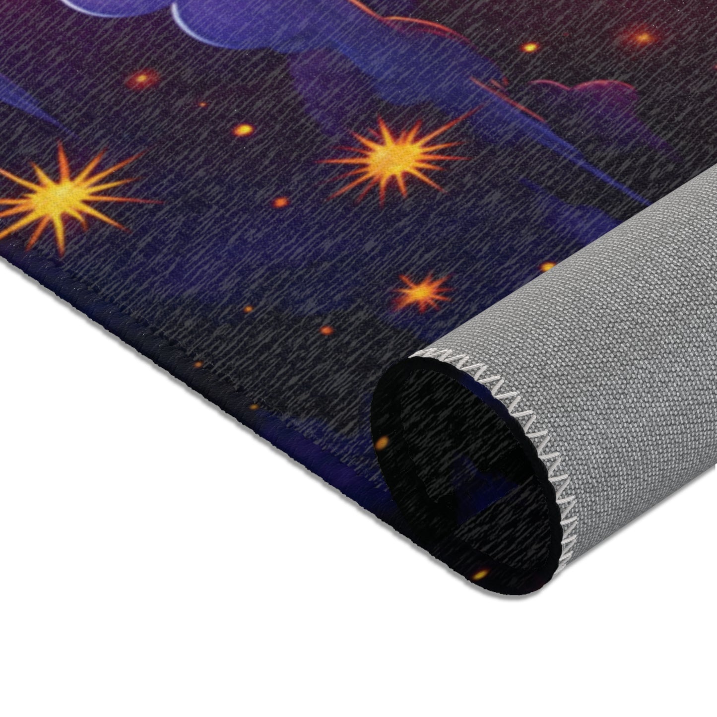 A close-up of a rolled-up mat featuring a colorful, star-filled night sky design on a dark background. Crafted from durable polyester, the mat’s edge shows visible stitching and the underside is a textured, light gray material.