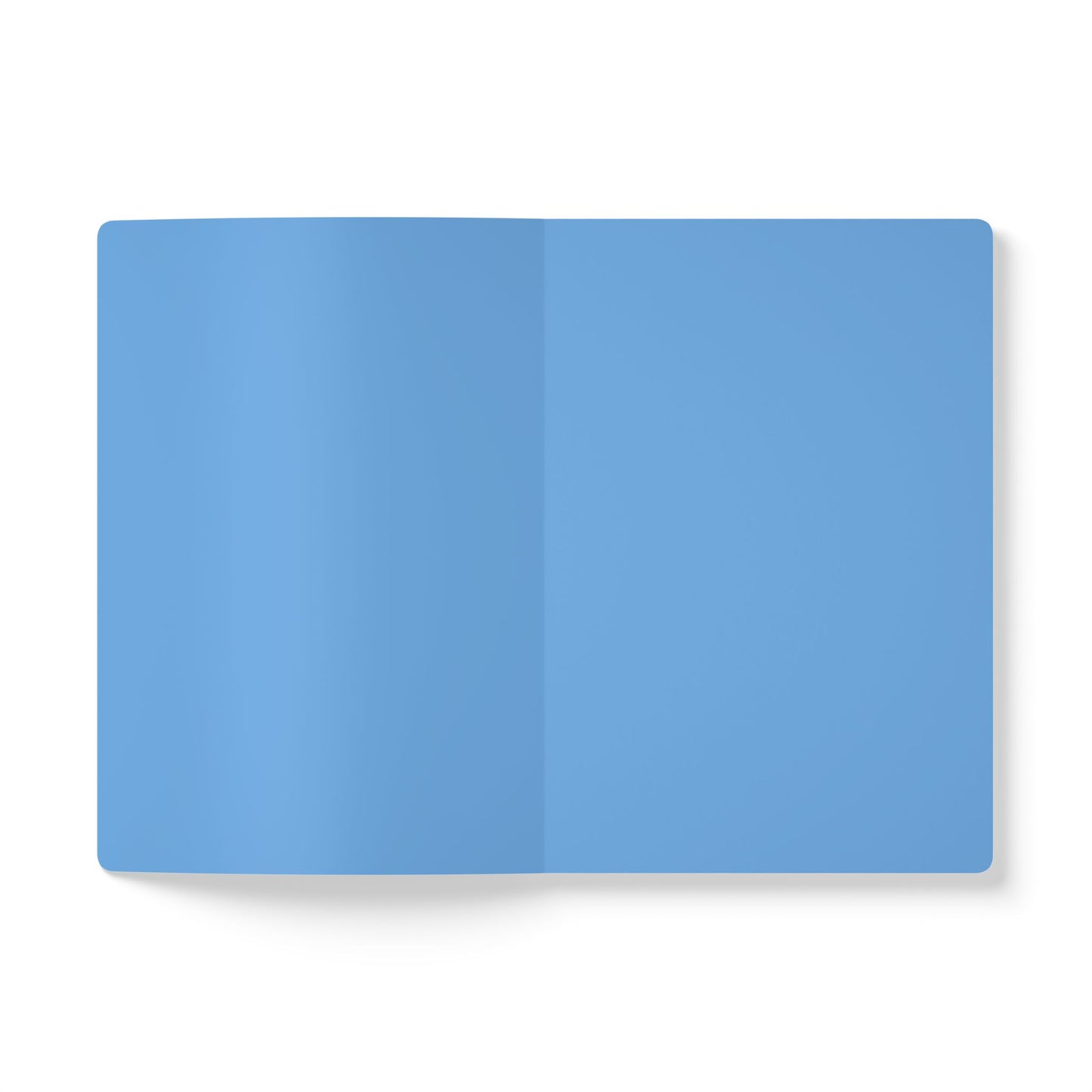 An open, blank creative journal with light blue pages is displayed against a white background. The notebook lies flat, showing a center fold and no text or markings. Shadows on the left add depth to this inviting space for daily journaling.