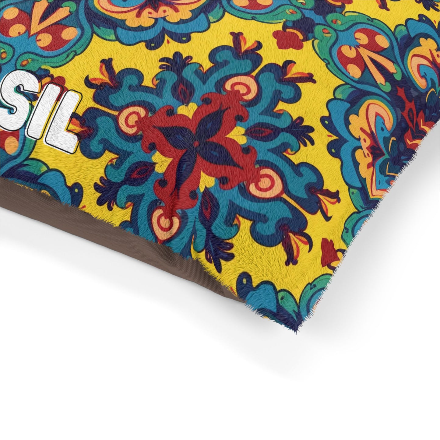 A vibrant custom dog pillow features a colorful, intricate pattern with swirling red, blue, and teal shapes on a yellow background. The partial white text SIL is visible on the left side, and the fabric appears textured and slightly fuzzy at the edge.