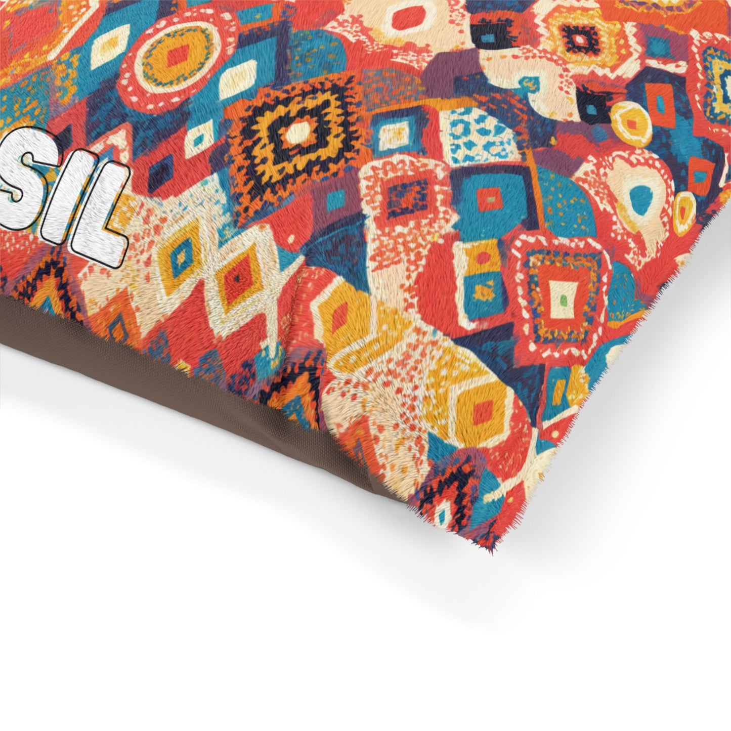 A close-up of a colorful, African-inspired fabric featuring a geometric, mosaic-like pattern with diamonds, squares, and abstract shapes in red, blue, yellow, cream, and orange tones. The edge of bold white text with a black outline is partially visible on the left.