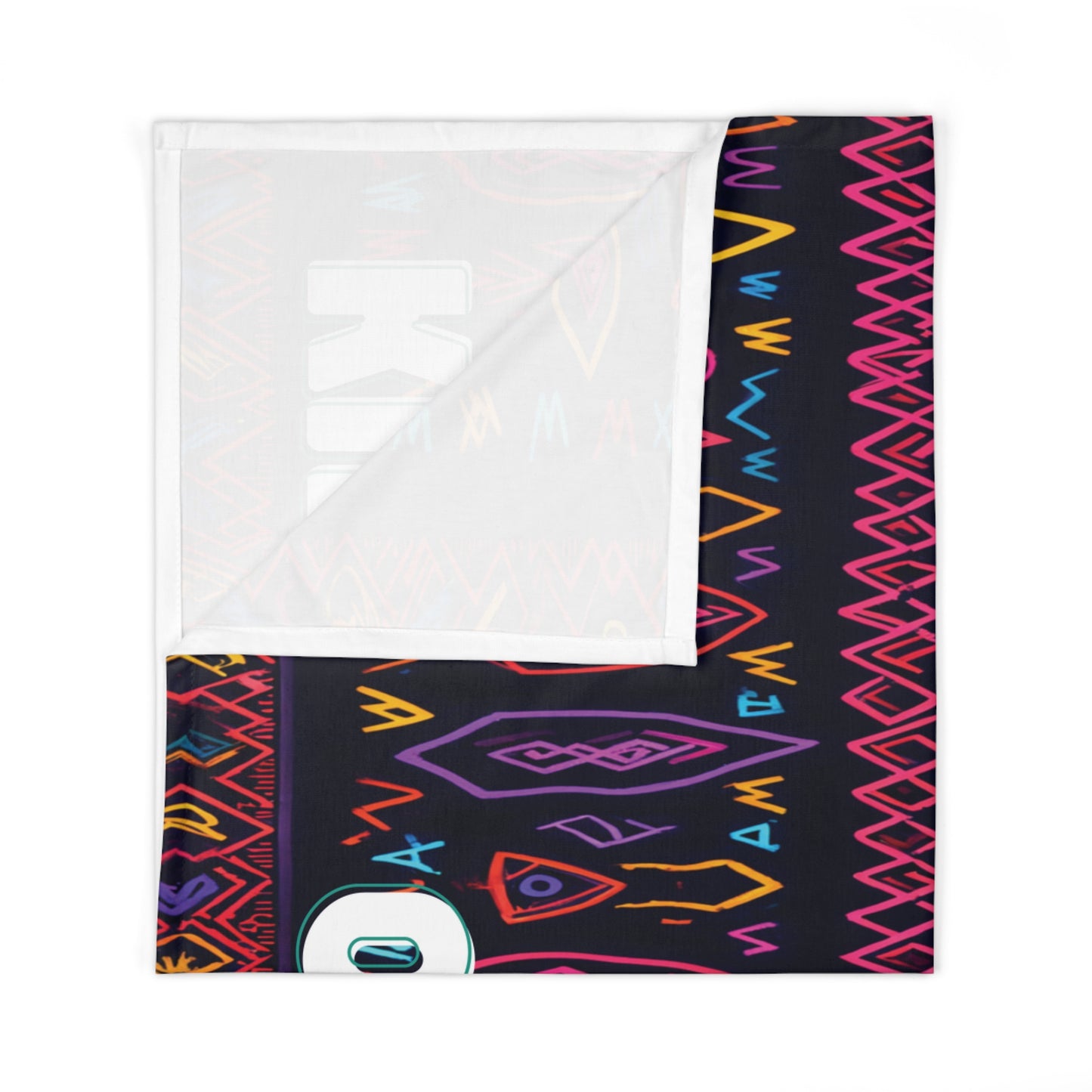 A folded blanket with a colorful geometric pattern featuring zigzags, diamonds, and arrow shapes in pink, orange, yellow, and blue on a dark background. This African-inspired decor piece is partially turned to show the white underside.