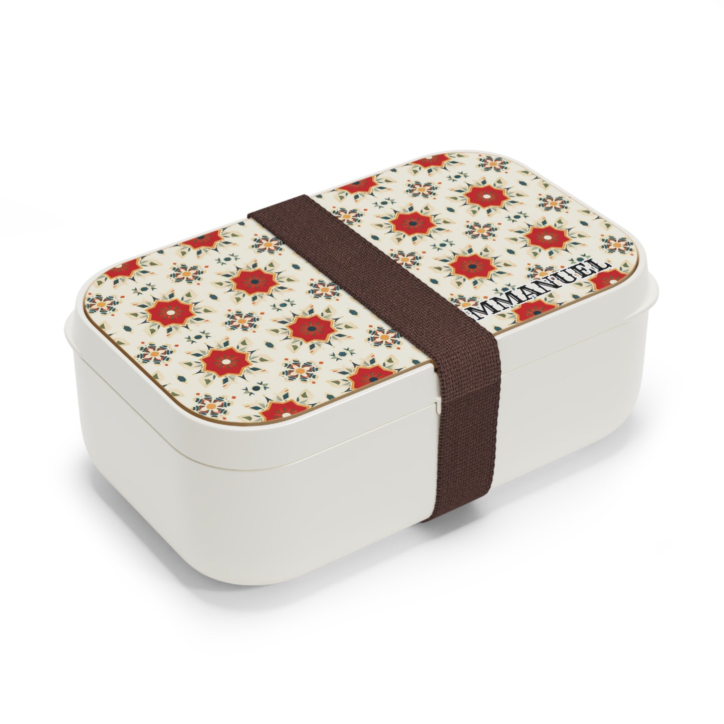 A personalized white bento lunch box with a lid featuring a red and beige floral pattern and the name “IMMANUEL” in one corner. A wide dark brown elastic band secures the lid, evoking an African-inspired touch. Background is plain white.