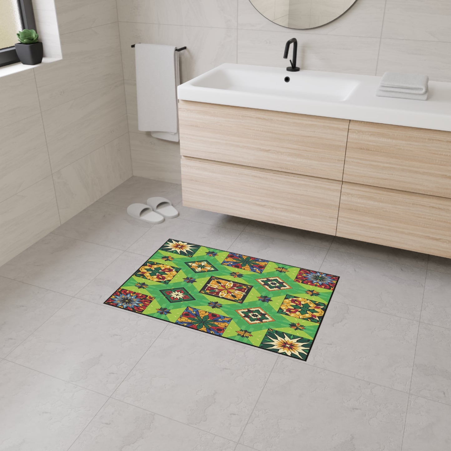 A modern bathroom with beige tiled walls and floor, a white sink with wood cabinets, a round mirror, white slippers, towel, and a vibrant green geometric-patterned mat featuring African-inspired aesthetics and non-slip rubber backing at the center.