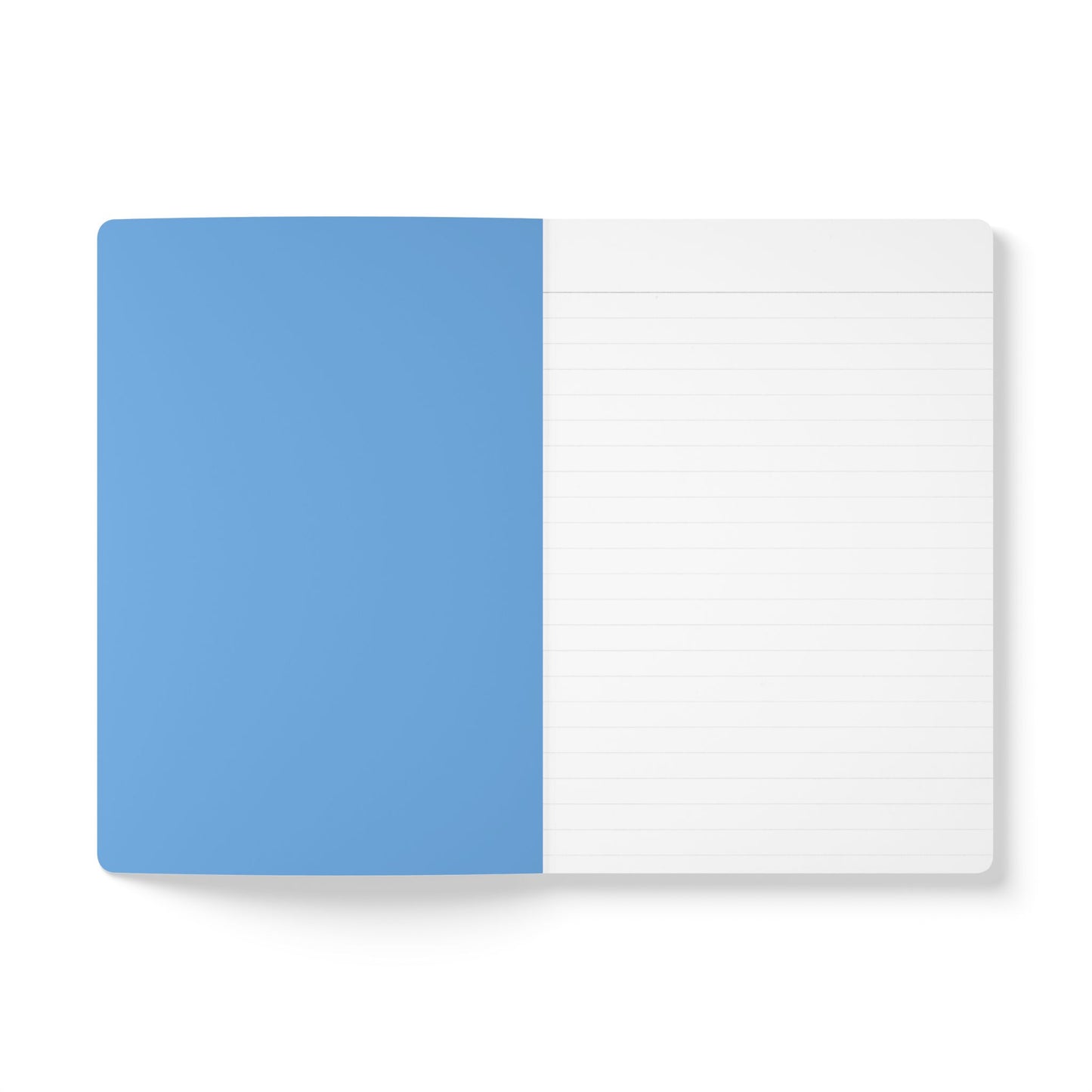 An open creative journal lies flat on a white surface. The left page is solid light blue and blank, while the right page is white with faint gray horizontal lines. The notebook has rounded corners and a minimal, clean design.