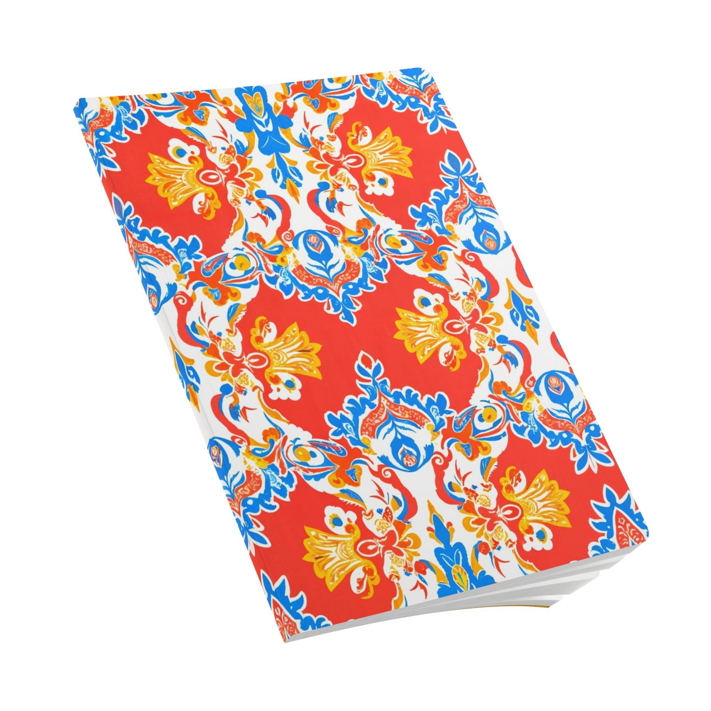 A closed African-inspired journal with a vibrant cover, featuring a symmetrical floral and paisley pattern in red, blue, yellow, and white. The ornate design pops against the bold red background. The notebook is photographed on a white surface.