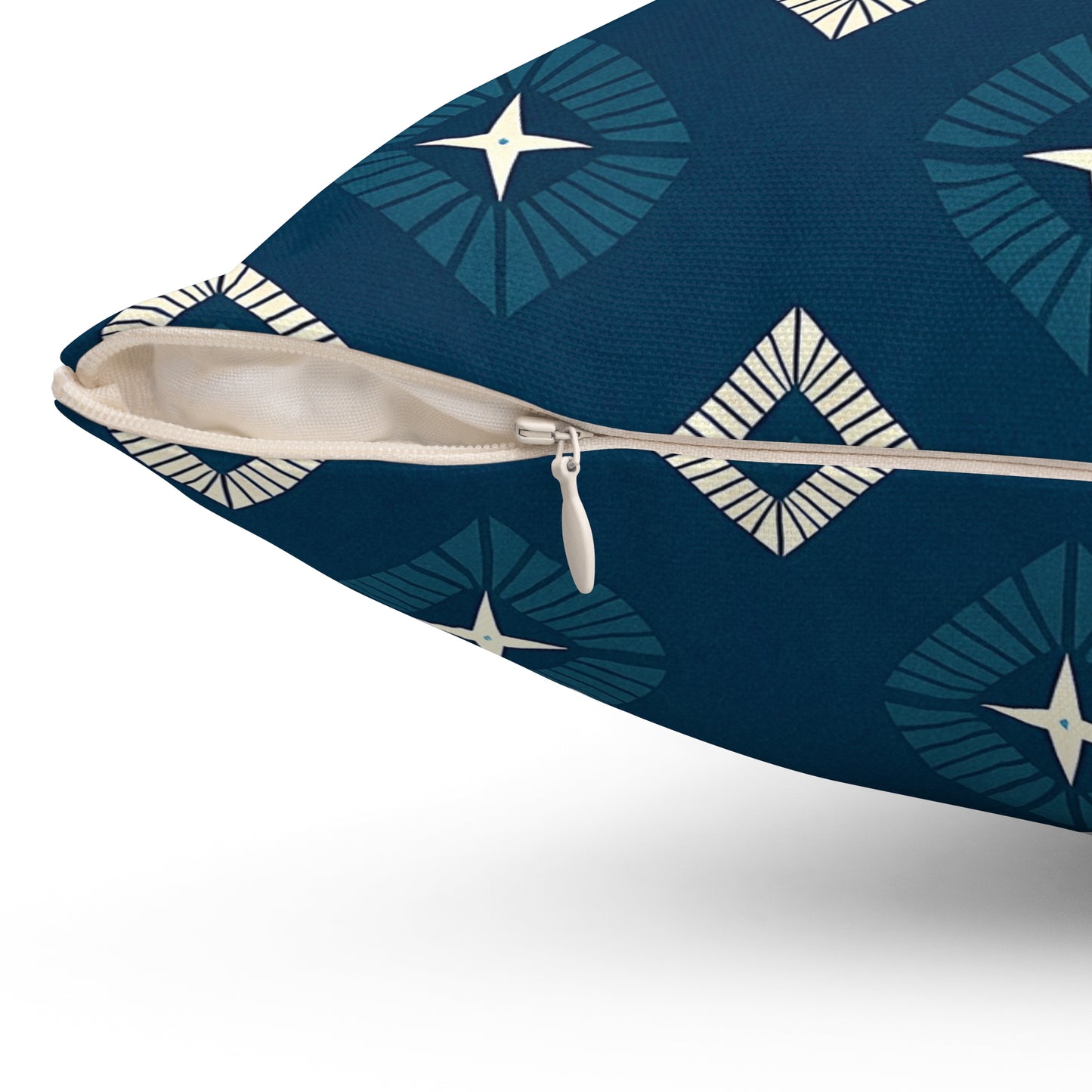 Close-up of a navy blue pillow with a beige zipper partially open. The pillow features vibrant patterns with diamond shapes and star motifs in cream and blue, adding a unique touch to your home decor. Textured fabric and the pillow’s edge are shown in the foreground.