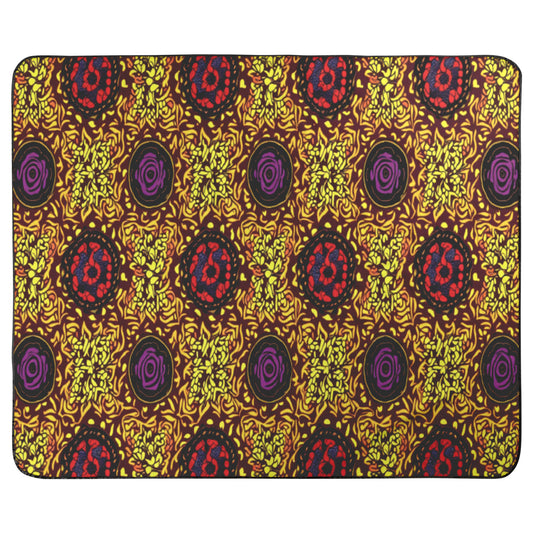 A rectangular mat with African-inspired patterns featuring clusters of yellow shapes, circular purple swirls, and red spots on a dark background. The design is vibrant and symmetrical, with rounded corners, a black border, and a plush fleece top.