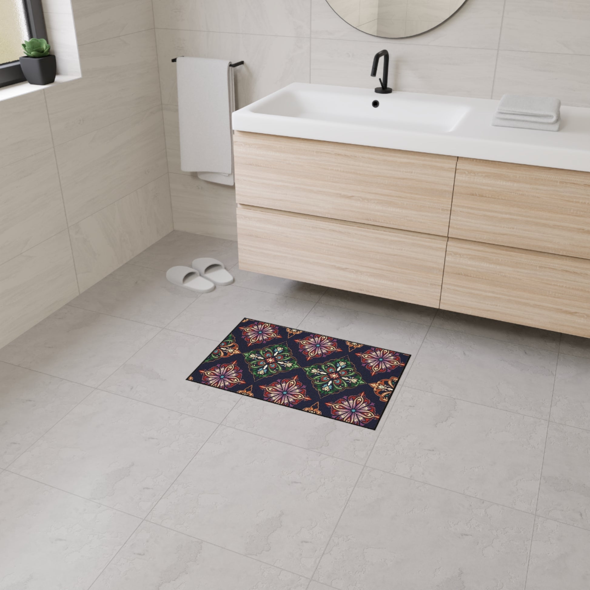 Modern bathroom with light tiled floor and walls, a wooden vanity with a white sink, black faucet, and round mirror. A colorful decorative mat featuring African-inspired aesthetics and non-slip rubber backing adds style. White slippers and folded towels are visible.